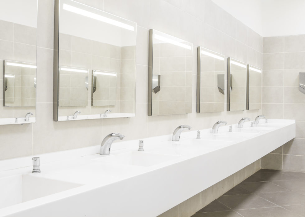 Bright commercial washroom with a row of touchless faucets and mirrors