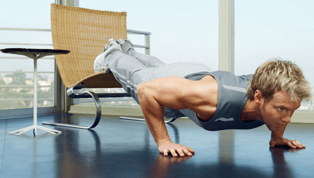 Man doing push-ups at home beside a chair