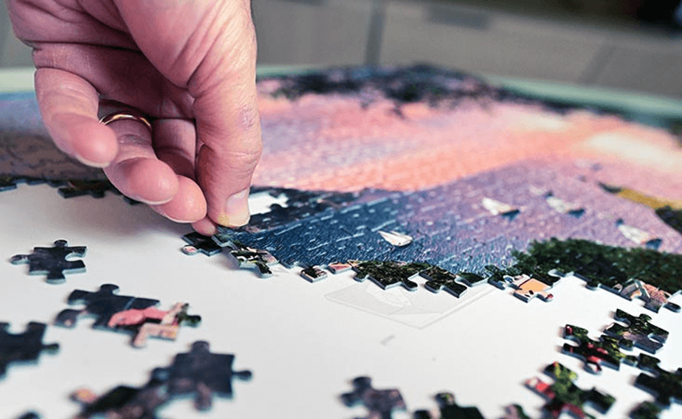 Hand placing a piece into a jigsaw puzzle