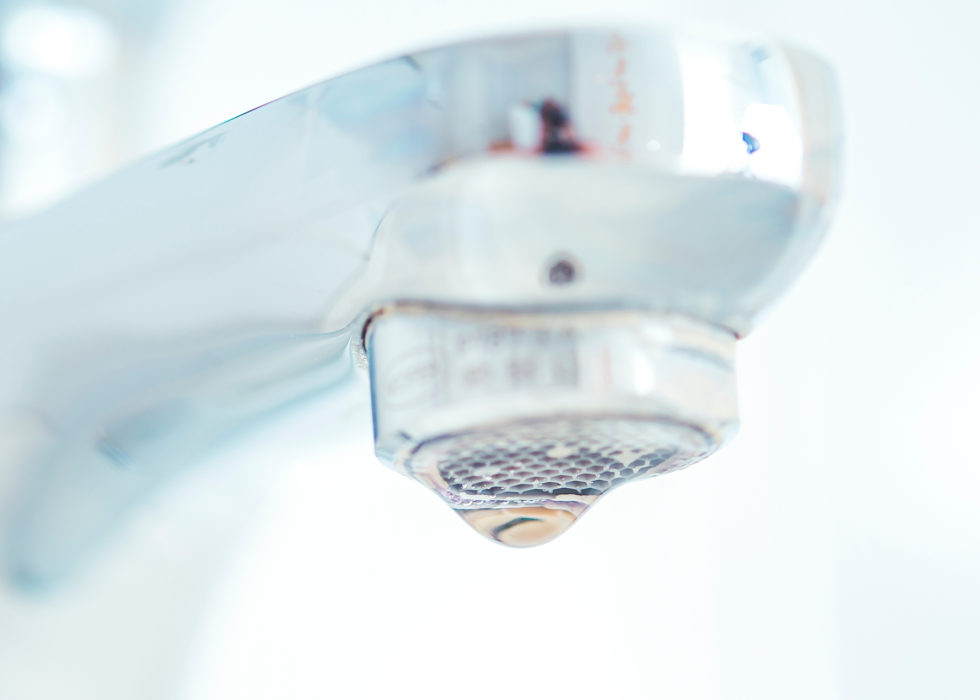 Close-up of a chrome faucet aerator with a water droplet